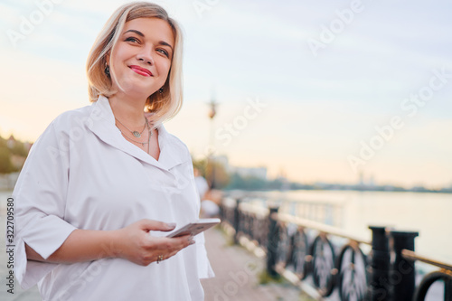 Attractive young woman using smartphone while walking down the city promenade.