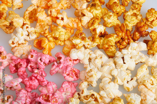 Different flavors of popcorn (cherry, caramel, salted, cheese tastes), close up background. Snacks and food for a movie wathcing photo