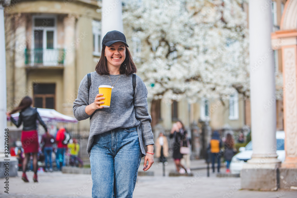 young stylish woman walking by street with coffee cup