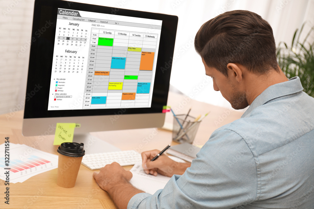 Man planning his schedule with calendar app on computer in office