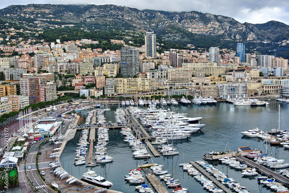 Monte Carlo, Monaco - Houses in bright colors on the shores of the Mediterranean Sea, a bay with moorings on which there are yachts, the sky with white-gray clouds.