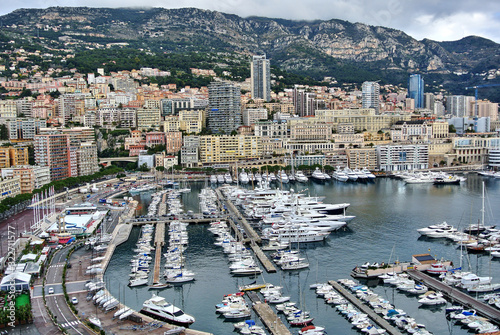 Monte Carlo, Monaco - Houses in bright colors on the shores of the Mediterranean Sea, a bay with moorings on which there are yachts, the sky with white-gray clouds.