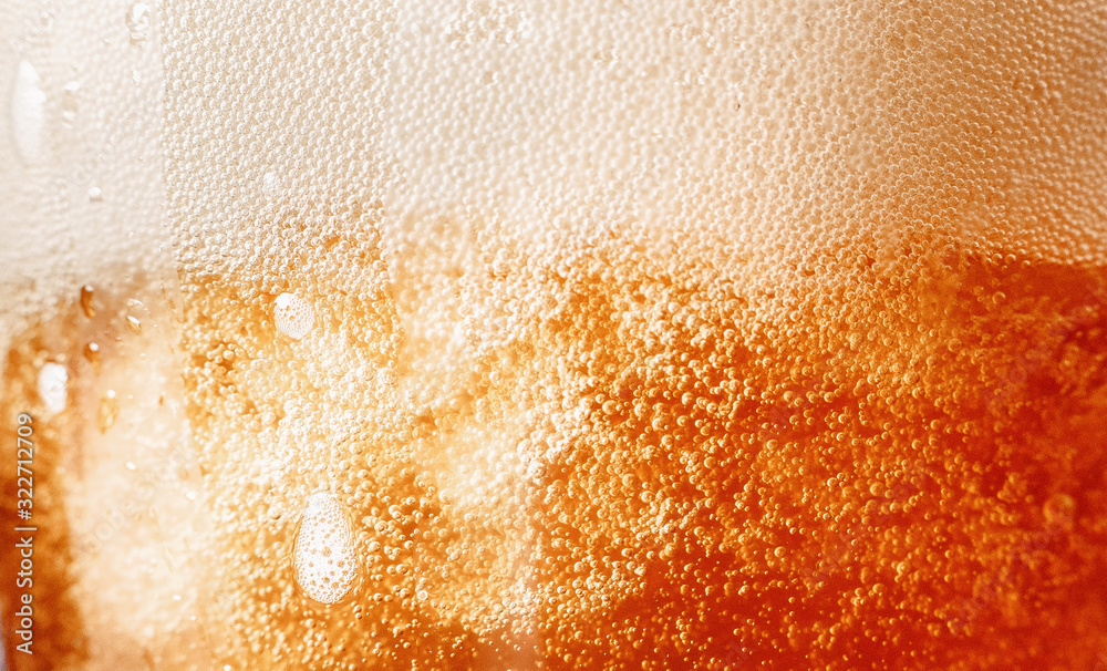 Close up gold background texture of yellow lager beer with froth and bubbles in glass, soft focus Close up gold background texture of yellow lager beer with froth and bubbles in glass, soft focus