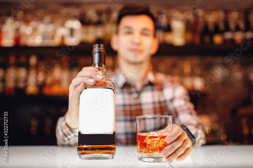 Photo Barman holds out glass of whiskey with ice to male visitor