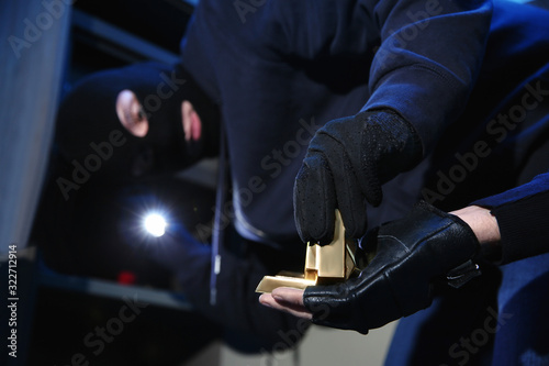 Thieves taking gold bars out of steel safe indoors at night