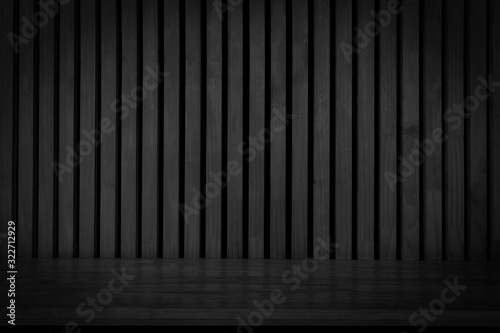 Black wooden board empty table in front of dark wood wall. Black wooden plank shelf on wood wall texture background.
