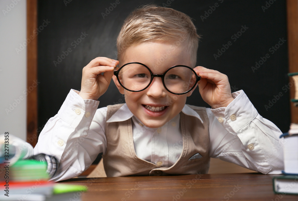 Cute little child wearing glasses at desk in classroom. First time at school Cute little child wearing glasses at desk in classroom. First time at school