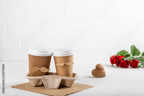 Two paper cups of coffee in cardboard tray on white background. Take out food. Cups with face of man and woman, couple in love, relations, love concept.