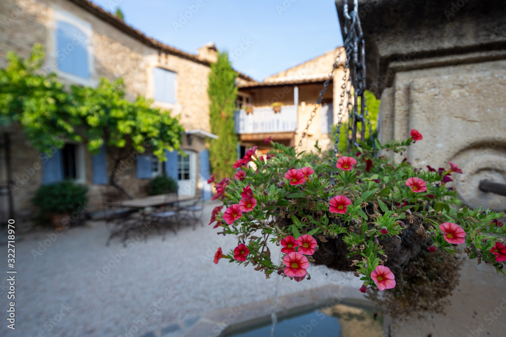 Hanging baskets on a fountain in the courtyard of a typical house in Provence, France