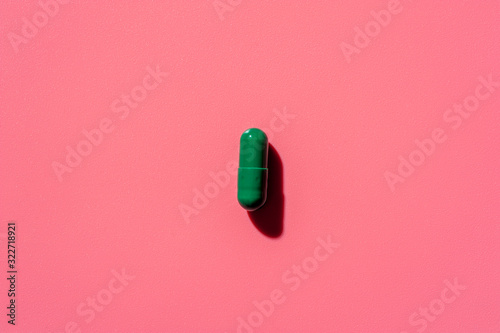 Photo Close-up of one pill lies on a pink surface