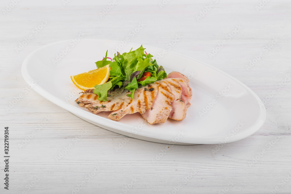 chicken breast with green salad on a white wooden background
