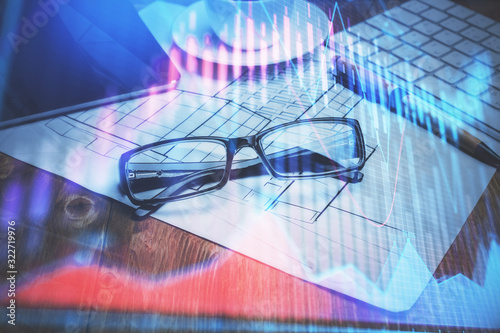 Financial chart hologram with glasses on the table background. Concept of business. Double exposure.