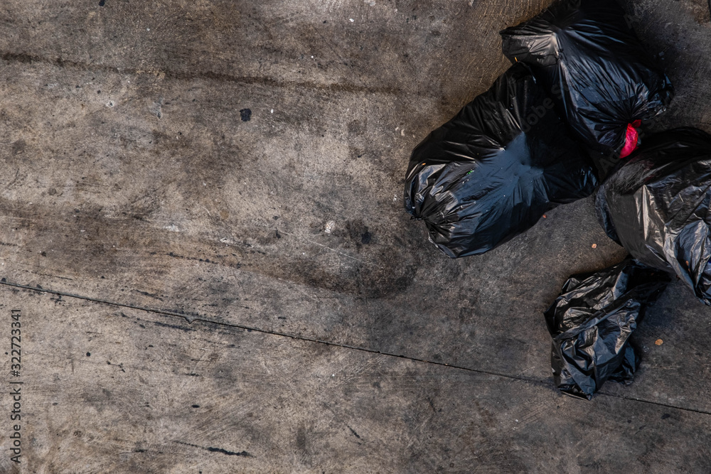 Many black garbage bags that are tied up On the sidewalk, roughly the footpath, viewed from the top view Many black garbage bags that are tied up On the sidewalk, roughly the footpath, viewed from the top view