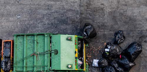 Green garbage truck Collecting a large number of black garbage bags that are tied up On the sidewalk To discard Viewed from the top view