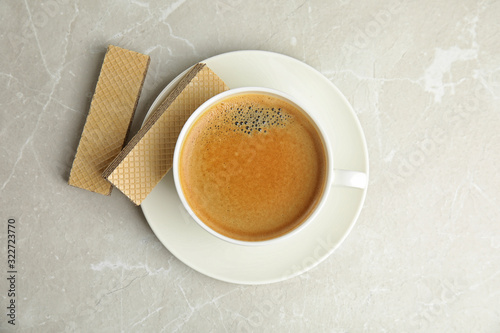 Delicious wafers and coffee for breakfast on grey marble table, flat lay