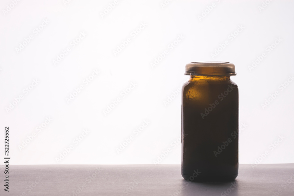 glass bottle of medicine on the table, tinting, selective focus, space for text on the left, white background glass bottle of medicine on the table, tinting, selective focus, space for text on the left, white background