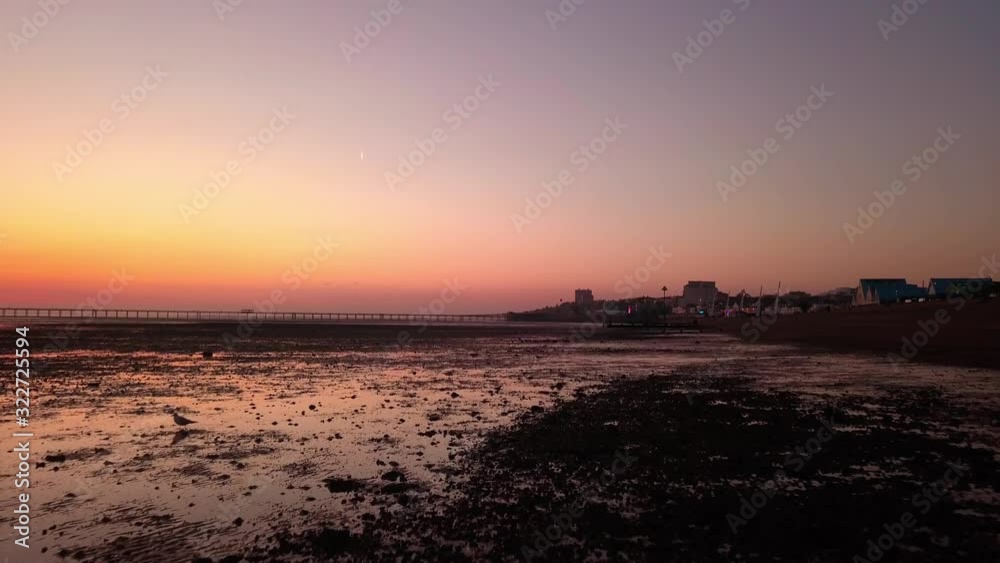 rolling skim across muddy empty beach with deep orange and red sky southend on sea essex February winter tide out rolling skim across muddy empty beach with deep orange and red sky southend on sea essex February winter tide out