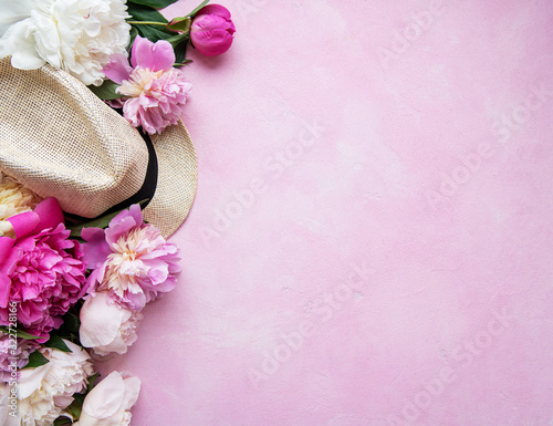 Pink peonies and hat on a pink concrete background