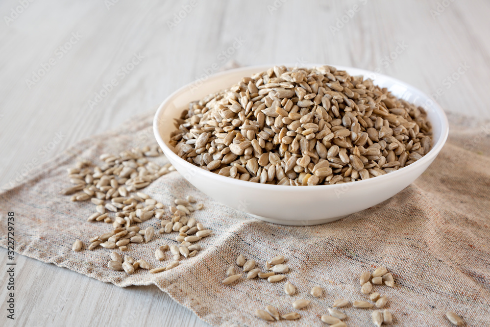 Raw Sunflower Seed Kernels in a white bowl on a white wooden background, side view. Close-up. Raw Sunflower Seed Kernels in a white bowl on a white wooden background, side view. Close-up.