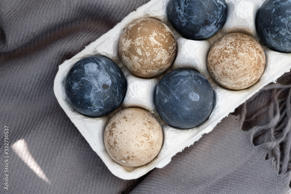 natural-dye Easter eggs lying in tray . Background with easter eggs. Naturally dyed eggs prepared for Easter on gray texture tablecloth background. Happy Easter card. 