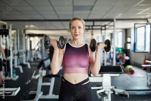 Young woman doing biceps workout with dumbbells
