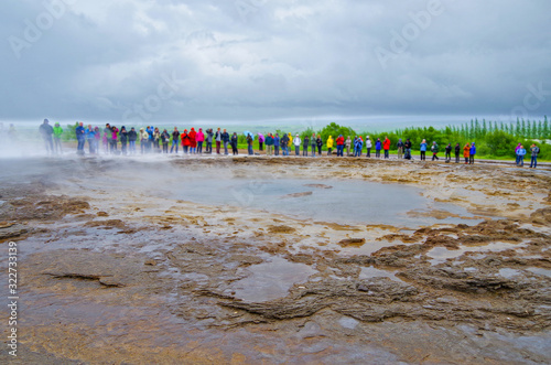 People waiting for Big Geysir erruption or Strokkur to errupt in geothermal field with hot springs and boiling water in national park on Iceland	 photo