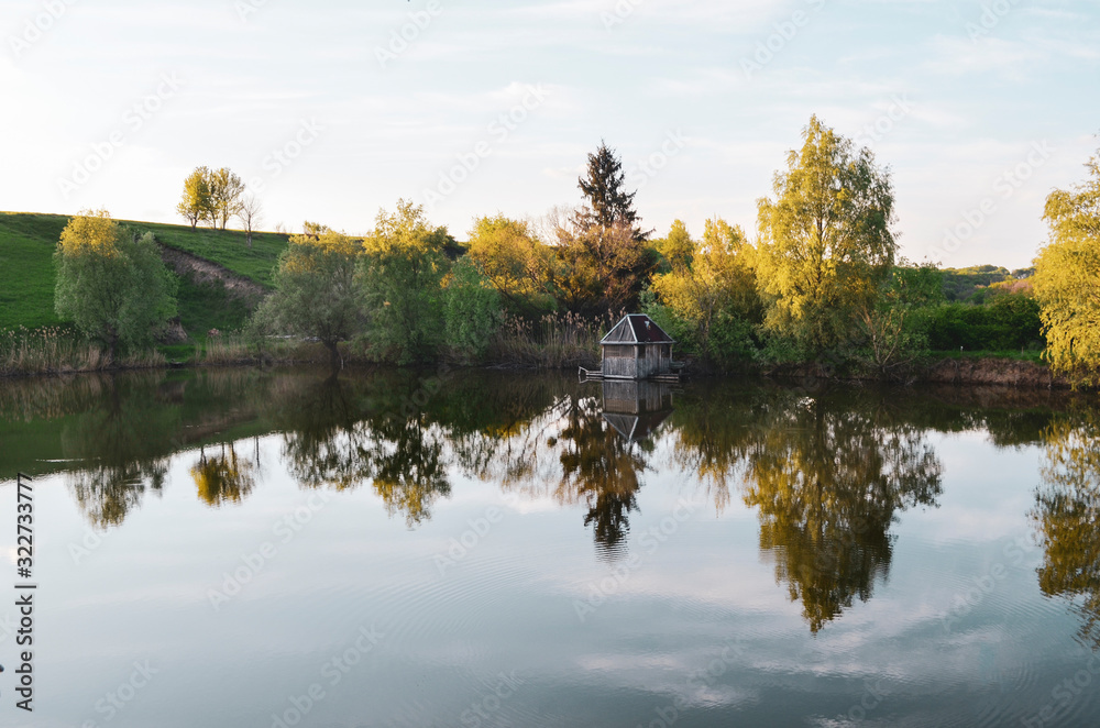 In summer, green lawns and trees over the river and in the river reflect the blue sky