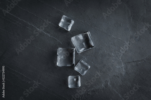 Crystal clear ice cubes on black table, flat lay