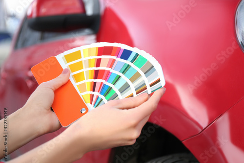 Woman with palette samples choosing color for painting car, closeup