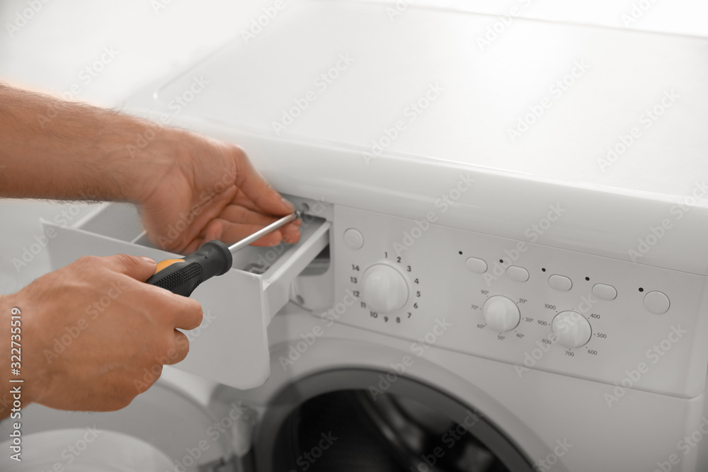Professional plumber repairing broken washing machine, closeup Professional plumber repairing broken washing machine, closeup