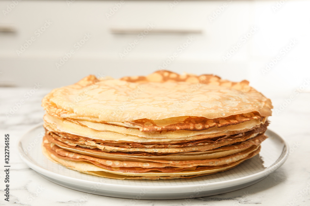 Stack of fresh thin pancakes on white marble table Stack of fresh thin pancakes on white marble table