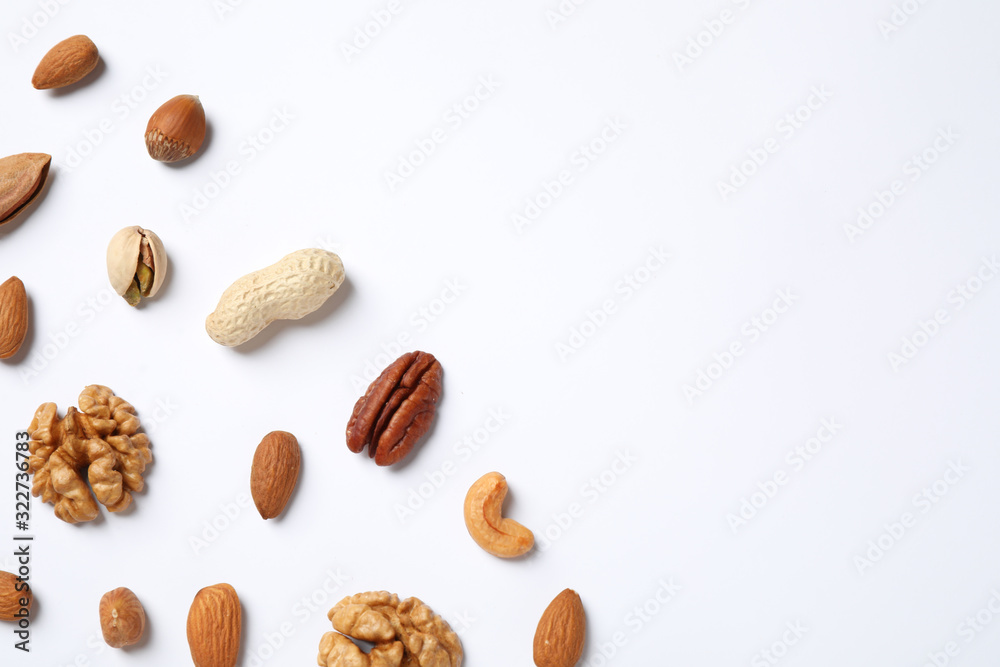 Different delicious nuts on white background, flat lay. Space for text
