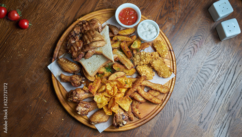 Photography An excellent beer snack is a set of chicken nuggets fries with parchment sauce on a stone tray