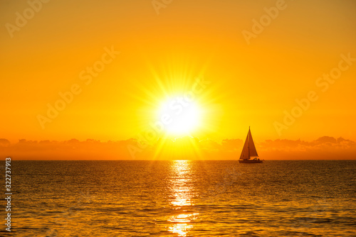 A sailboat sailing with the sunrise sun