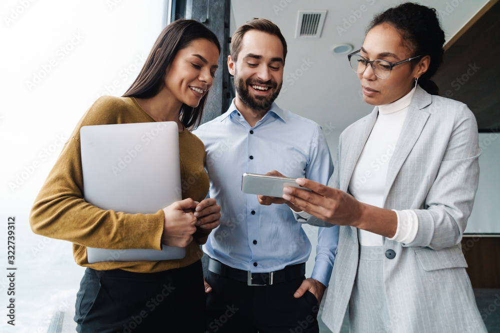 © Drobot Dean - Portrait of colleagues talking and using cellphone while working in office