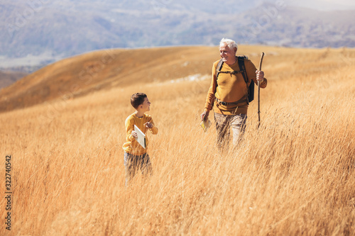 Senior man with grandson on country walk in autumn.