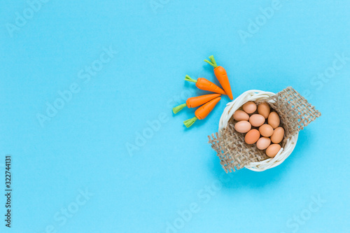 Eggs in the basket and carrots on blue paper texture background, healthy food concept, food handmade craft item photo