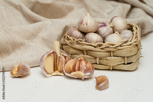 garlic solo in a wicker basket on a linen background.next to it is a canvas bag. eco condiments
