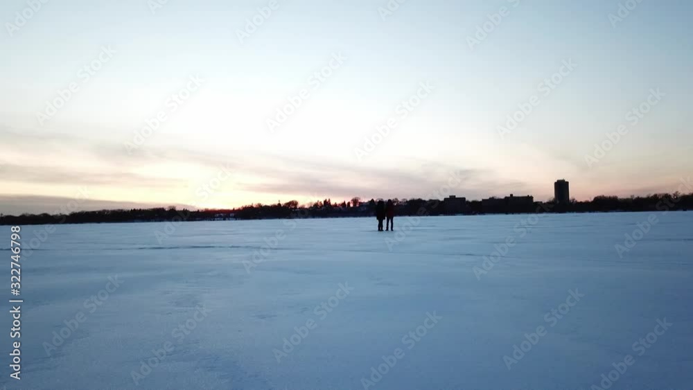winter landscape two person standing on a frozen lake during blue hour winter landscape two person standing on a frozen lake during blue hour