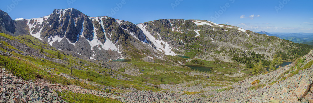 Large panorama of the mountain landscape. Large panorama of the mountain landscape. Valley with lakes, spring greens and snow on the rocky slopes.