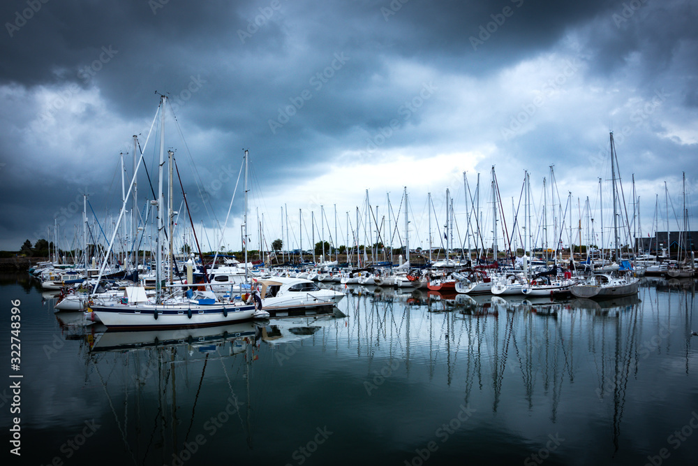 Normandy, France. Sailing and fishing boats in marina in cloudy day. Beautiful cloudscape and its reflection in water. Dramatic lighting, majestic nature. Marine background. Nautical travel concept.