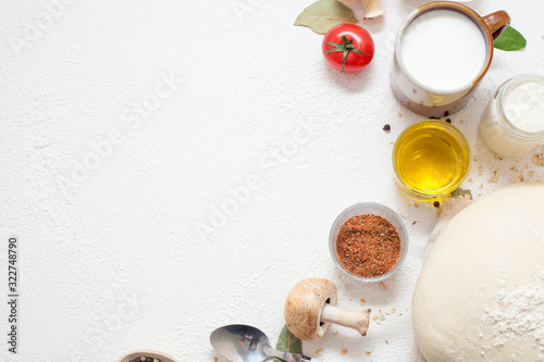 Ingredients for cooking on a white background, including milk, eggs, spices and dough with olive oil and black pepper in polka dots, with copy space. The concept of cooking and recipes.