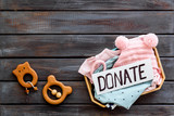 Charity concept. Donate text on box with clothes on dark wooden background top-down copy space