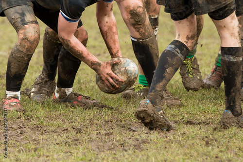Dirty hands holding a rugby ball in a rugby game