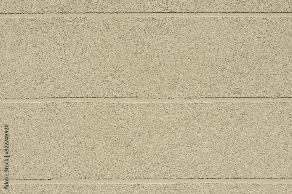 Fototapeta premium Fassade mit beige gelblichen Putz und horizontal verlaufenden Sichtfugen als Gestaltungselement zur Auflockerung von großen Flächen