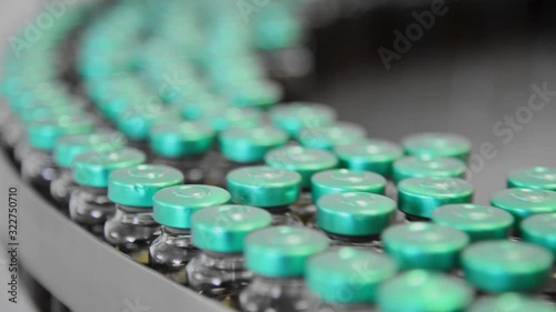 Production line conveyor with moving glass bottles ampoules in the factory