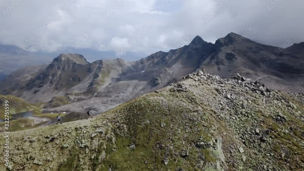 Epic aerial shot of two persons hiking up the edge of a mountain in Switzerland Epic aerial shot of two persons hiking up the edge of a mountain in Switzerland