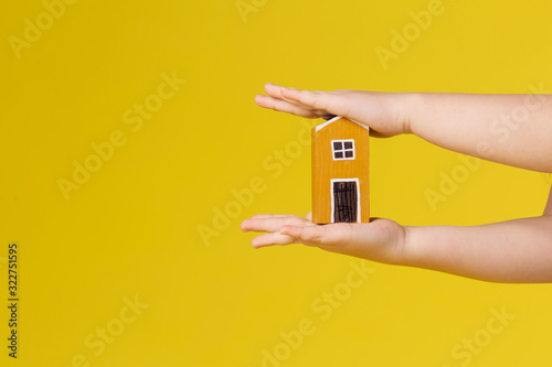 Children's hand holds the house. Yellow copyspace background place for text. Positive color joyful. Concept mortgage loan realtor real estate agency. Home Purchase Promotion Sale