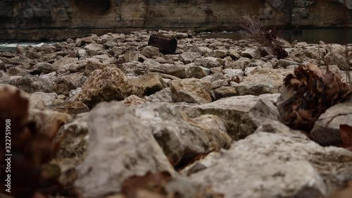 Riverbed of Running Water and Rocks during the Winter by bluff, slider shot photo