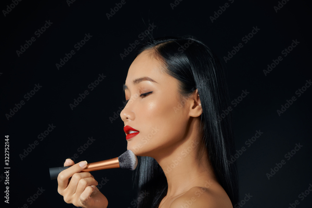 Fototapeta premium portrait of young beautiful woman with brush for make-up